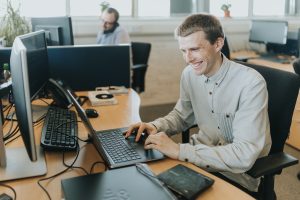 Piran Technologies male employee sat working at a laptop computer smiling