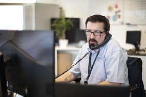 An IT support technician on the phone in an office