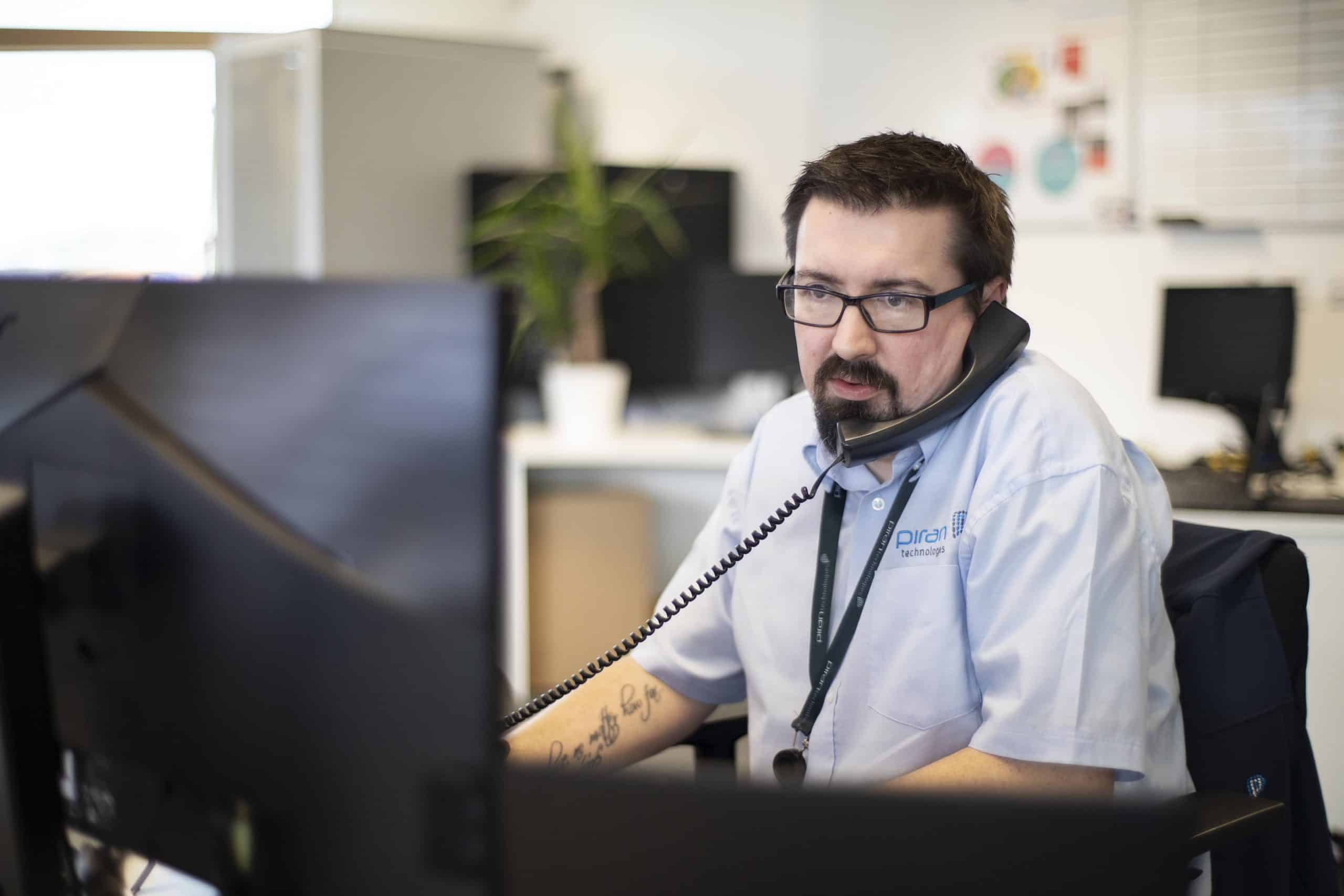 An IT support technician on the phone in an office